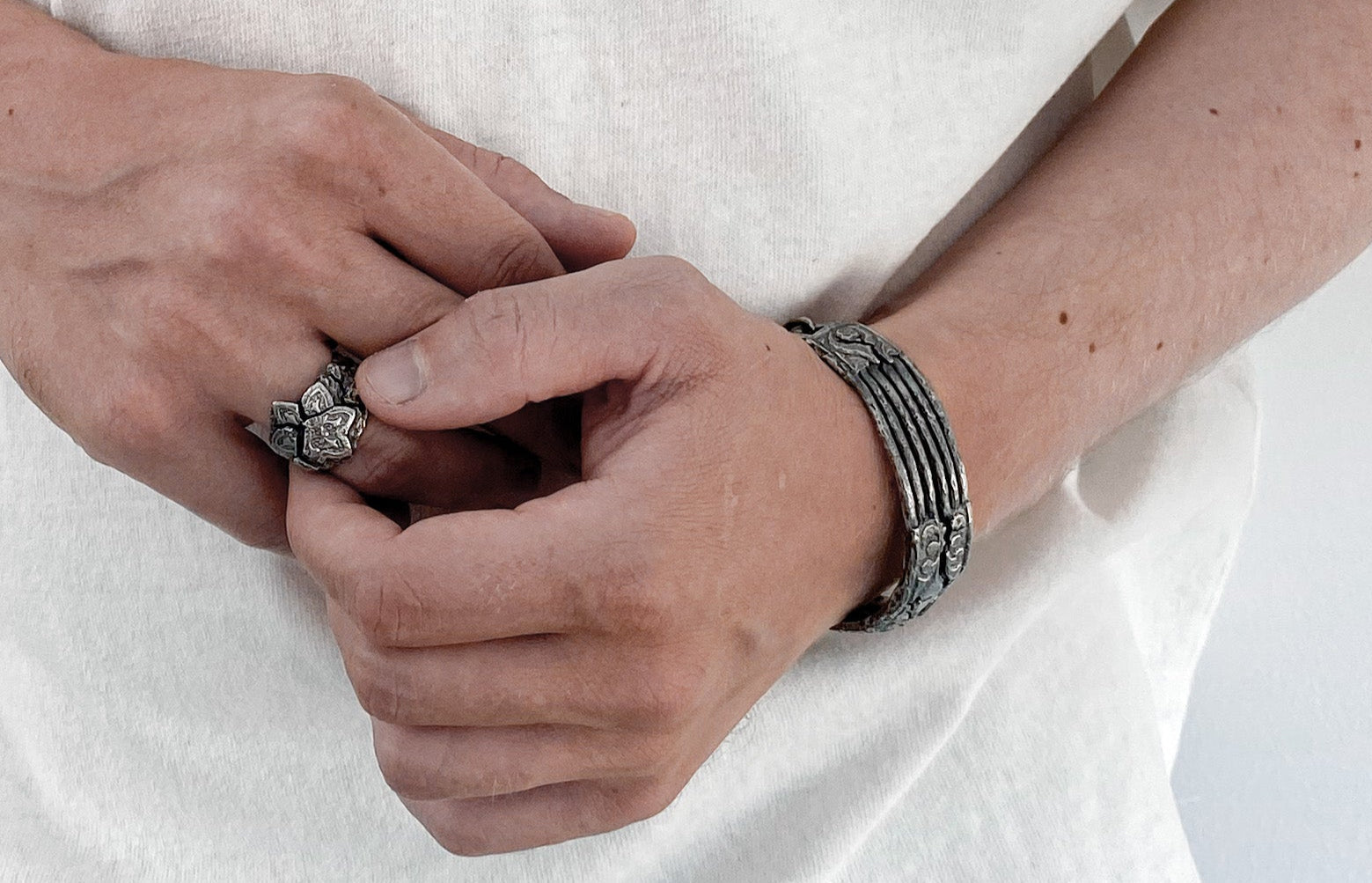Close-up of hands with silver rings and bracelets on a white background