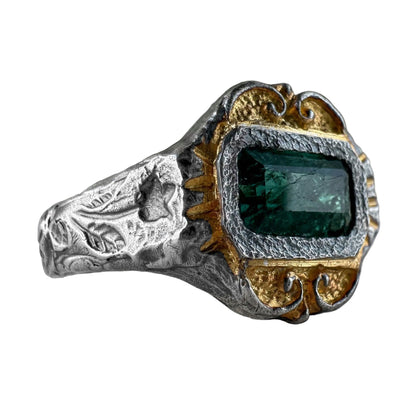 Silver and gold ring with a green gemstone on a white background