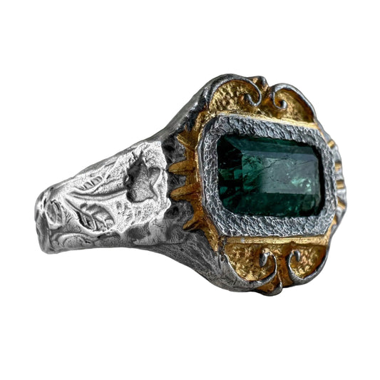 Silver and gold ring with a green gemstone on a white background